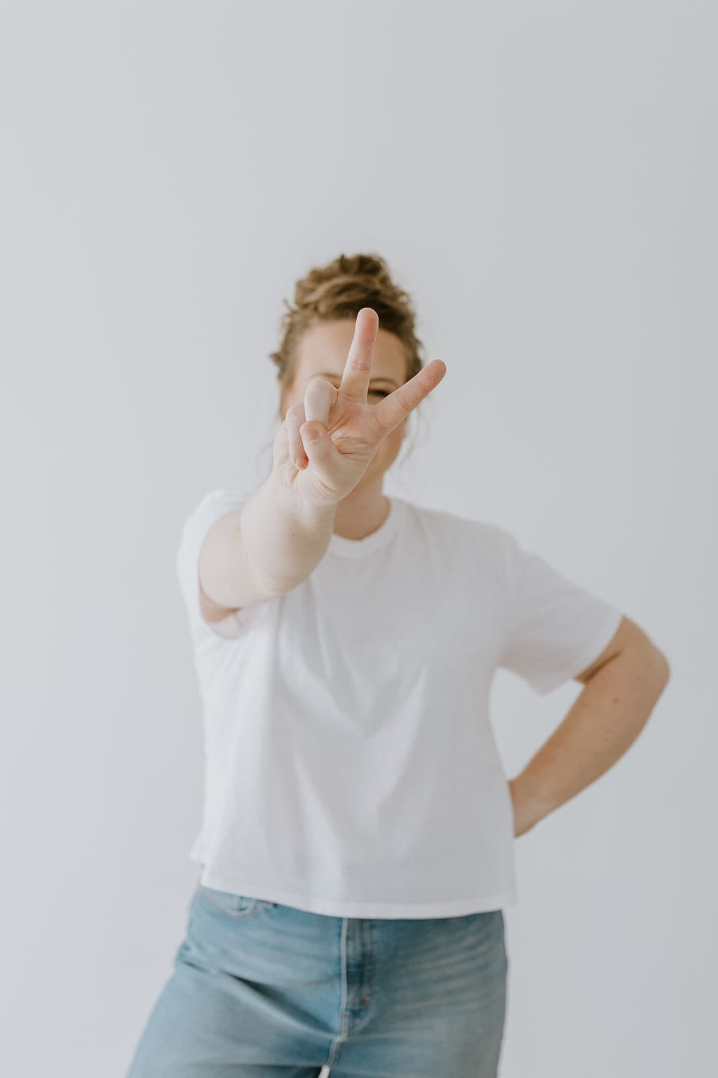 Megan Nakazawa in a white tee, smiling and holding up a peace sign